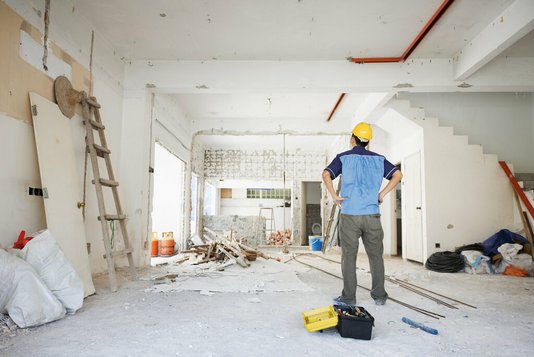 hausbau-haus-bauen-eigenleistung-handwerker-rohbau-04 Handwerker betrachtet den Rohbau von innen.